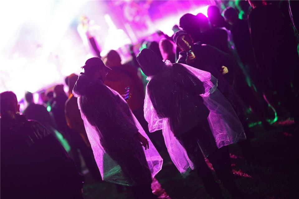 Besucher stehen am Abend mit Regenkleidung vor der Bühne des Festival Rocken am Brocken.Matthias Bein/dpa
