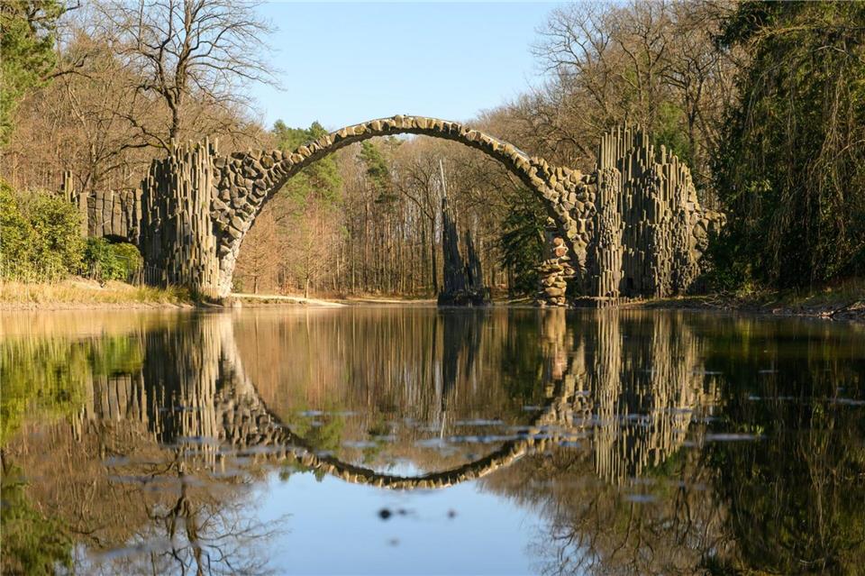 Besuchermagnet Rakotzbrücke: Das imposante Bauwerk aus Basalt- und Feldsteinen spannt sich mit 35 Metern Länge über den See.Robert Michael/dpa