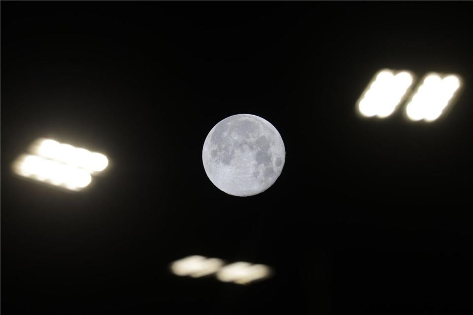 Blick auf den Mond zwischen Straßenlaternen in Riedlingen. Thomas Warnack/dpa