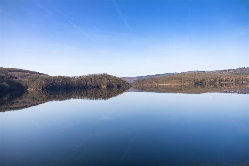 Blick auf den stillen Rursee, in dem sich der blaue Himmel spiegelt. (Archivbild)Thomas Banneyer/dpa
