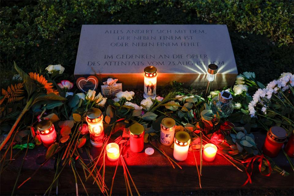 Blumen und Kerzen befinden sich am Gedenkstein unweit des Tatorts für die Opfer des Terroranschlags von Solingen am ersten Jahrestag. (Archivbild) Thomas Banneyer/dpa