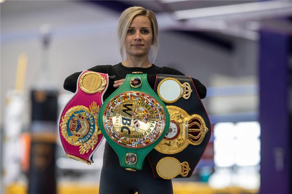 Boxerin Tina Rupprecht mit ihren drei WM-Gürteln - einer fehlt noch.Peter Kneffel/dpa