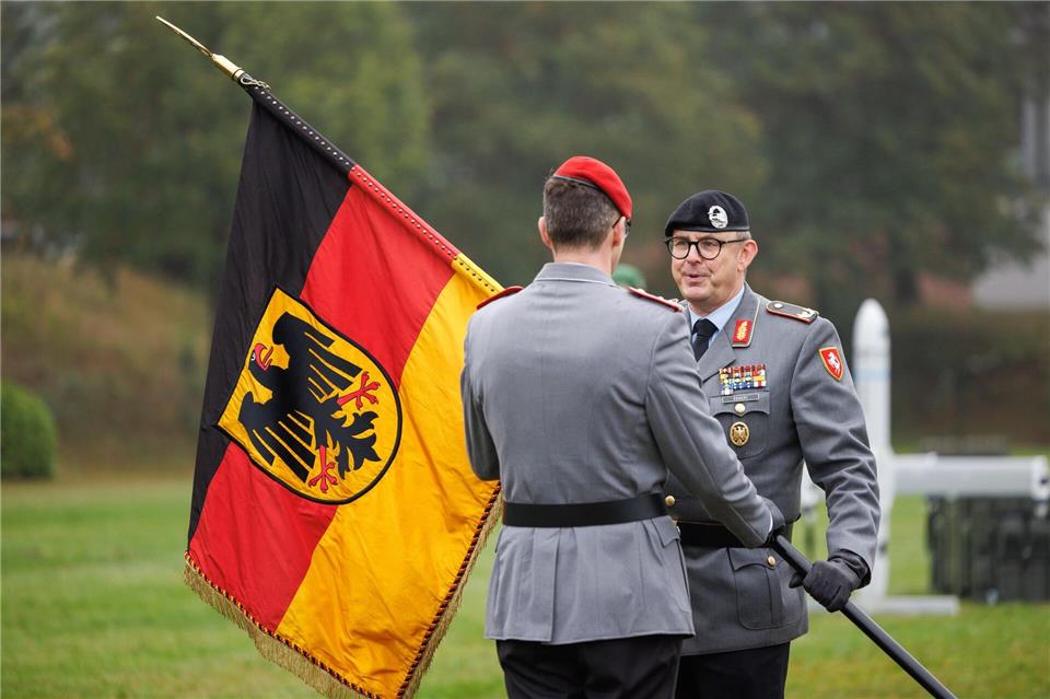 Brigadegeneral Marco Eggert (r) übergibt eine Deutsche Fahne beim Feierlichen Appell für das neu aufgestellte Artilleriebataillon 215 in der General-Feldmarschall-Rommel-Kaserne.Friso Gentsch/dpa
