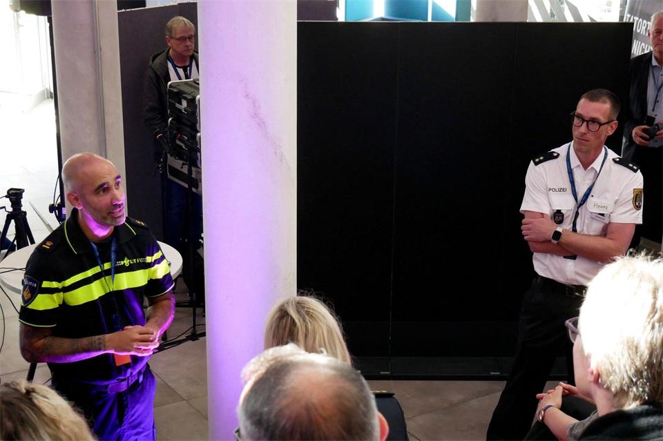 Bryan Sewberath Misser (l), Inspektor der niederländischen Polizei, und Henry Dieringer, Polizeioberrat der Polizei Sachsen-Anhalt, sprechen vor Teilnehmern des 1. True-Crime-Hackathon der sachsen-anhaltischen Polizei.Sebastian Münster/dpa