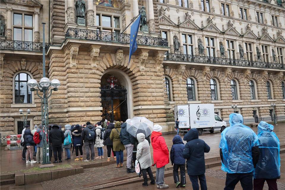 Bürgerinnen und Bürger warten in einer Reihe vor dem Rathaus. Christian Charisius/dpa