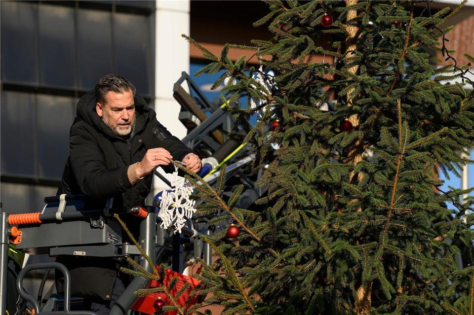 Bürgermeister Christian Belke (parteilos) bringt gespendeten Baumschmuck „“Little Ugly Christmas Tree“ an.Swen Pförtner/dpa