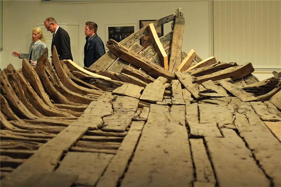 Bundeskanzler Friedrich Merz (2.v.l, CDU) geht mit Museumsdirektorin Astrid Cohrs-Dreessen (l) nach einer Pressekonferenz im Schifffahrtsmuseum Nordfriesland an dem „Zuckerschiff“ vorbei.Marcus Brandt/dpa