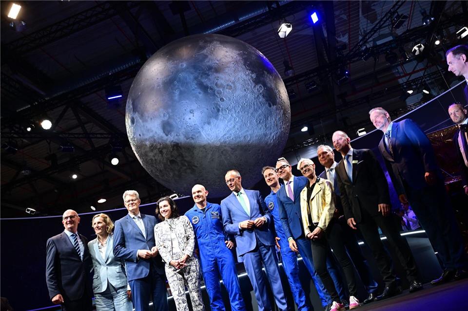 Bundeskanzler Friedrich Merz (6.v.l, CDU) steht unter anderem mit den beiden Esa-Astronauten Alexander Gerst (5.v.l) und Matthias Maurer (7.v.l) während eines Rundgangs auf der Internationalen Luft- und Raumfahrtausstellung (ILA).Sebastian Gollnow/dpa