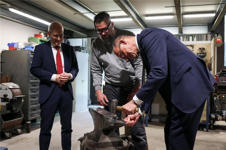 Bundeskanzler Friedrich Merz greift in einer Hamburger Schlosserei zum Hammer.Christian Charisius/dpa