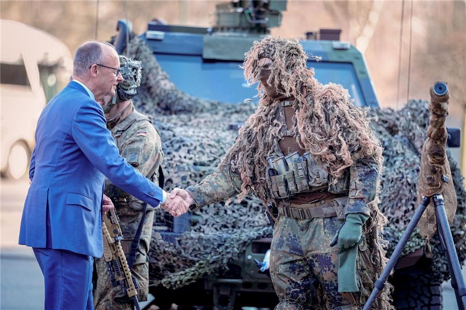 Bundeskanzler Friedrich Merz (l, CDU) wird bei der Verleihung des Fahnenbandes an das Wachbataillon in Berlin von einem Scharfschützen begrüßt.Kay Nietfeld/dpa