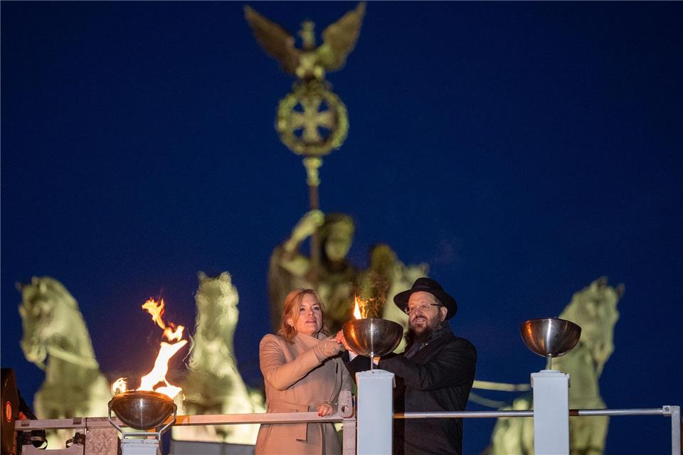Bundestagspräsidentin Julia Klöckner (CDU) und Rabbiner Yehudi Teichtal entzünden am Brandenburger Tor während einer festlichen Zeremonie die Lichter am Chanukka-Leuchter mittels einer Fackel.Soeren Stache/dpa