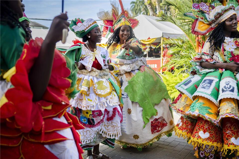 Bunt gekleidete Gäste feiern im Garten des Präsidentenpalastes von Suriname.Remko De Waal/ANP/dpa