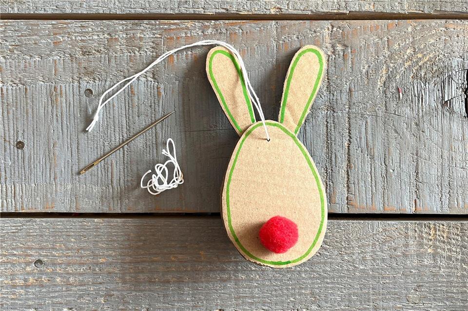 Bunte Bommel befestigen, mit einem Stift die Konturen umfahren und am Ende mit der Nadel einen Faden zum Aufhängen befestigen.DIY Academy/dpa-tmn