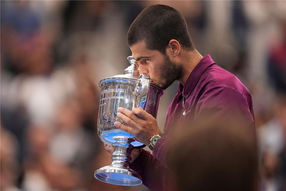 Carlos Alcaraz küsst nach seinem Sieg bei den US Open in New York die Trophäe.Seth Wenig/AP/dpa