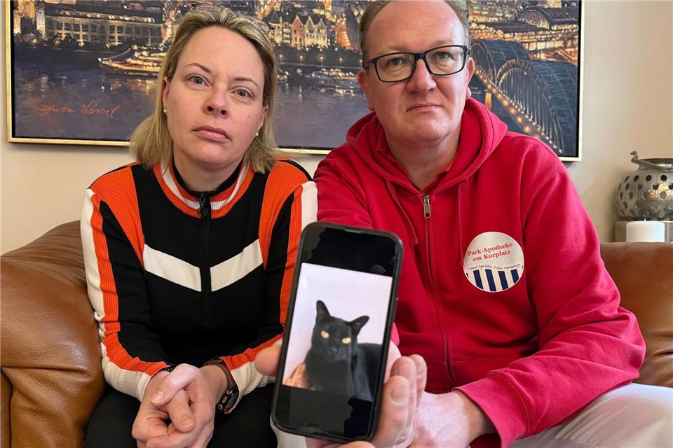 Catharina Majert und ihr Mann Gunnar zeigen auf einem Smartphone ein Foto ihrer Bombay-Katze Aramis.Volker Bartels/dpa