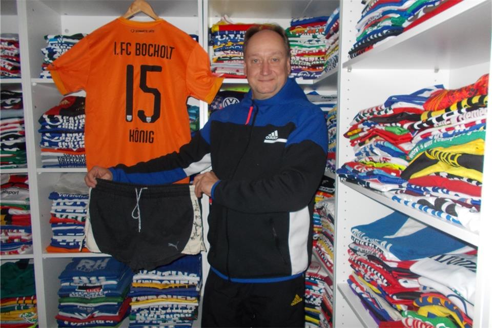 Christian König inmitten seiner Trikotsammlung: In der Hand hält er die Hose von Jürgen Tänzer aus dem Aufstiegsspiel 1977. Das orangefarbene Trikot ist das aus der aktuellen Saison. Es trägt den Namen von Königs Namenvetter Sven König, der seit dieser Saison für den 1. FC Bocholt aufläuft.privat