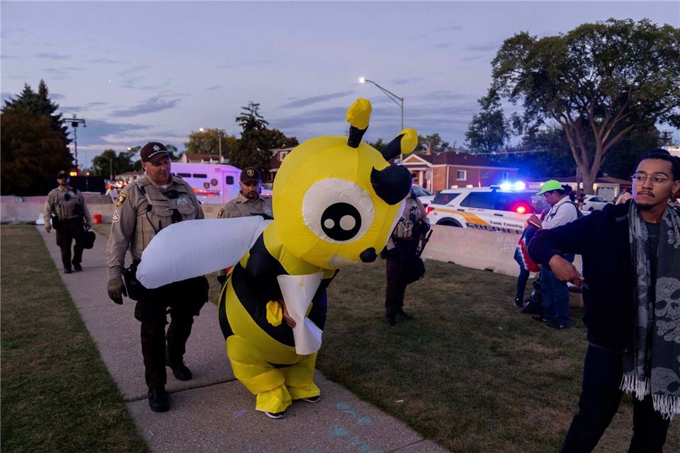Cook County Sheriffs ziehen einen Demonstranten in einem Kostüm zurück, während sie eine Ausgangssperre vor der US-Einwanderungs- und Zollbehörde in Broadview, Illinois, durchsetzen.Adam Gray/FR172090 AP/AP/dpa