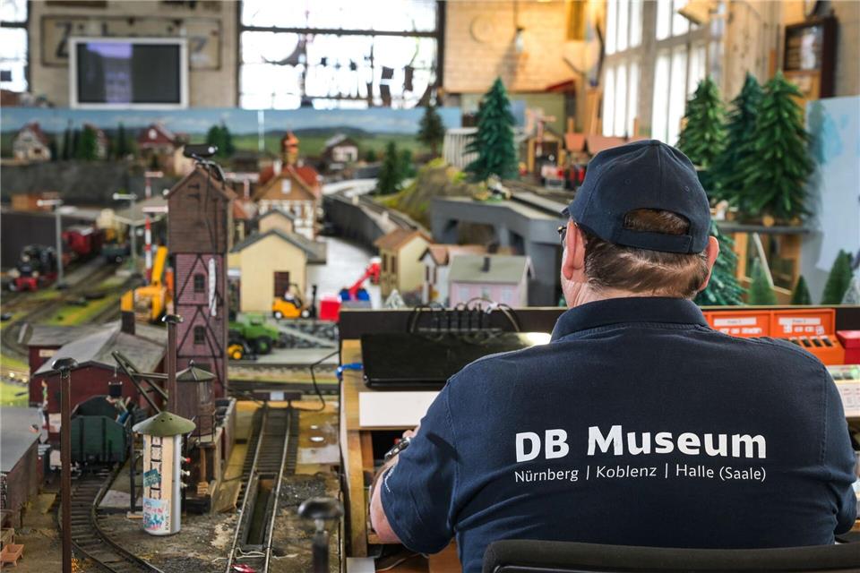 DB Museum Halle: Hans-Christoph Lichtenfeld sitzt mit einem T-Shirt mit der Aufschrift DB Museum, am Steuerungspult der Modellbahnanlage, Spurweite G. Heiko Rebsch/dpa