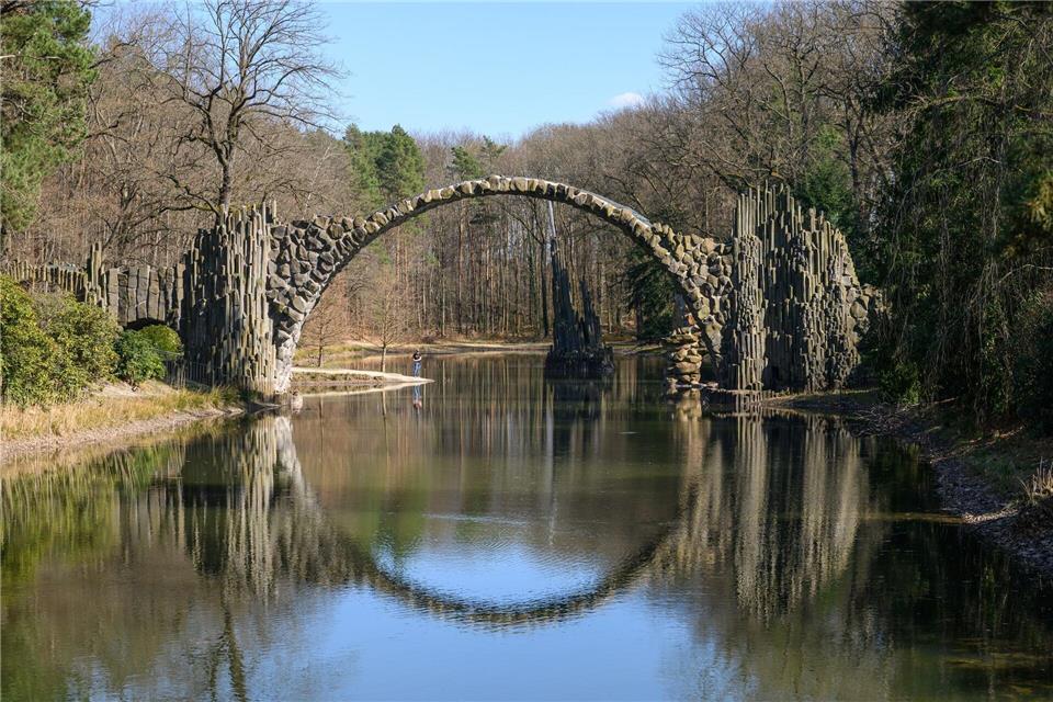 Dank einer Spiegelung im See wirkt die Rakotzbrücke wie ein Rundbogen.Robert Michael/dpa