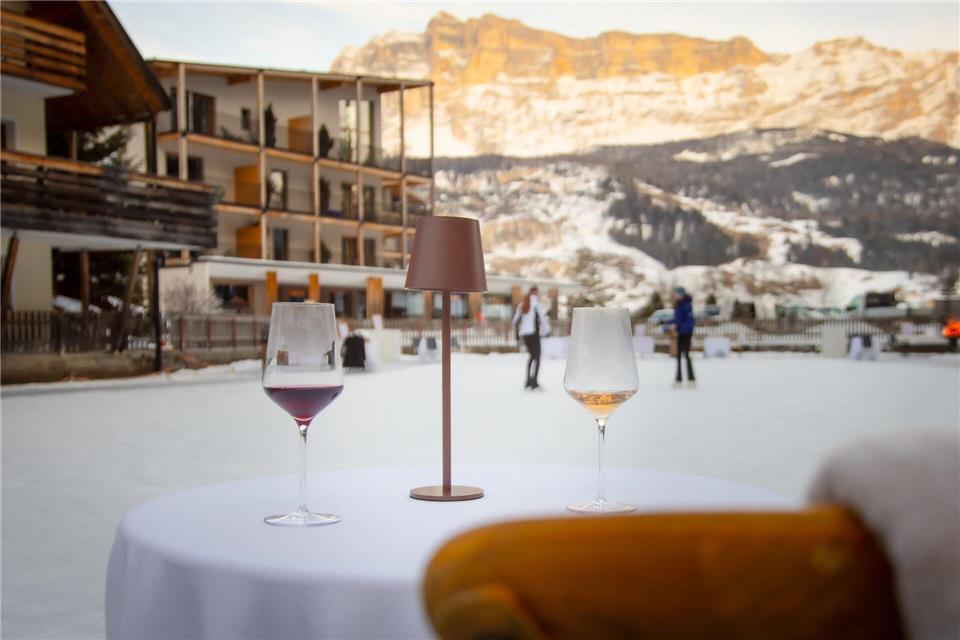 Darauf ein Prost: In der Ferne leuchten die Berge, während sich einige Mutige selbst für ein Tänzchen aufs Eis wagen. Manuel Glira/Alta Badia/dpa-tmn
