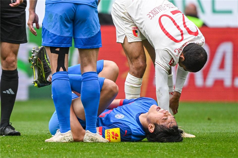 Das Aus für Shuto Machino: Der Kieler Angreifer liegt in Augsburg verletzt am Boden.Armin Weigel/dpa