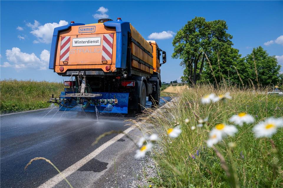 Das Fahrzeug des Winterdienstes ist im Einsatz, um den Asphalt zu kühlen.Jacob Schröter/dpa
