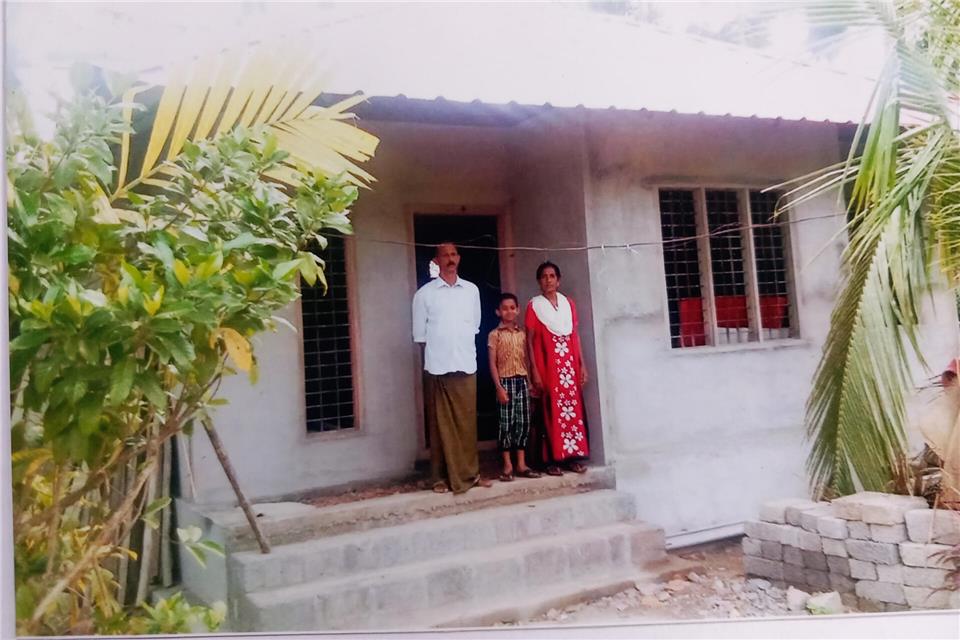 Das Foto zeigt Vater Sebastian (54), Mutter Thresiamma (47) und Sohn Sebin (9) der Familie Padinjareveedu aus Pacha Chekkidikadu, Kerala, vor ihrem neuen Haus.
