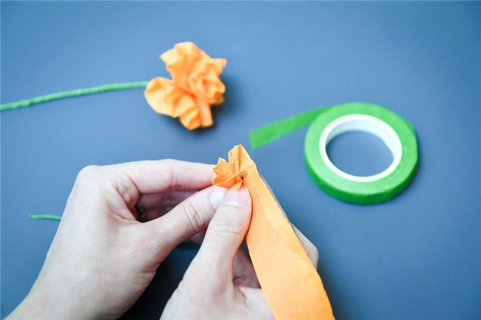 Das Krepppapier nicht zu eng um den Basteldraht wickeln - wenn dabei kleine Falten entstehen, wirkt die Blume am Ende realistischer.Zacharie Scheurer/dpa-tmn