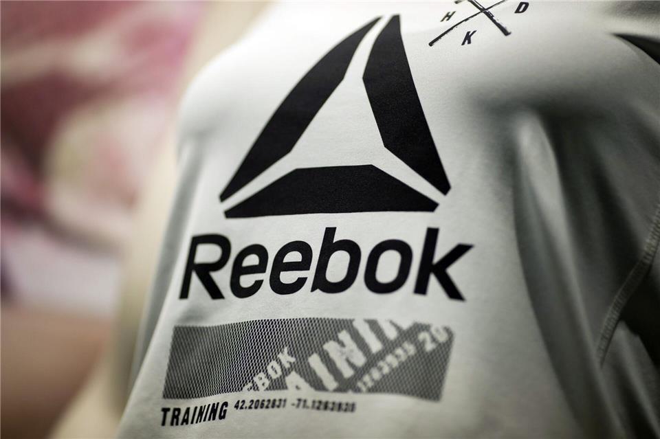 Das Reebok-Logo auf einem Shirt. (Archivbild)Daniel Karmann/dpa