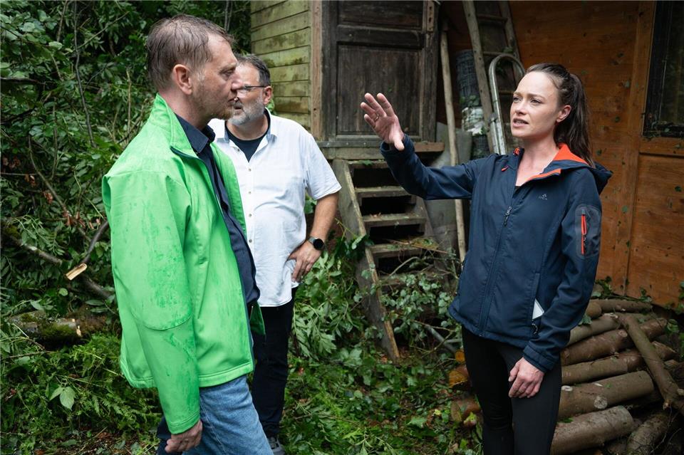 Das Unwetter hat einen Imbiss am Amselsee verwüstet - Sachsens Ministerpräsident Michael Kretschmer spricht mit der TV- und Eventköchin Verena Leister. Sebastian Kahnert/dpa