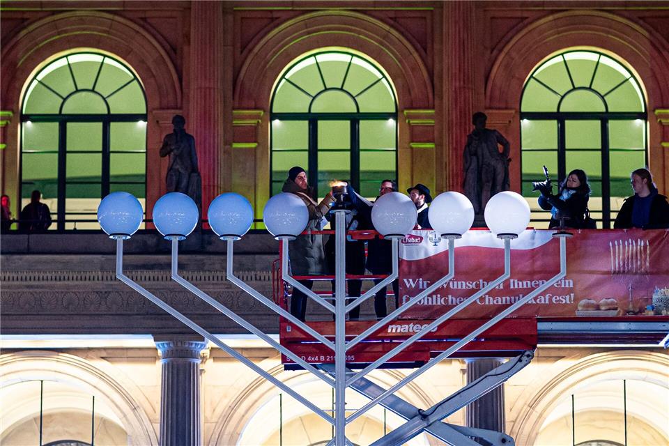 Das erste Licht am Leuchter wird entzündet.Moritz Frankenberg/dpa