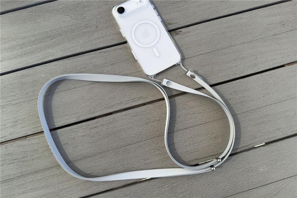 Das neue Crossbody-Band von Apple wird durch kleine Löcher in den iPhone-Hüllen geschlaut und damit befestigt.Andrej Sokolow/dpa/dpa-tmn