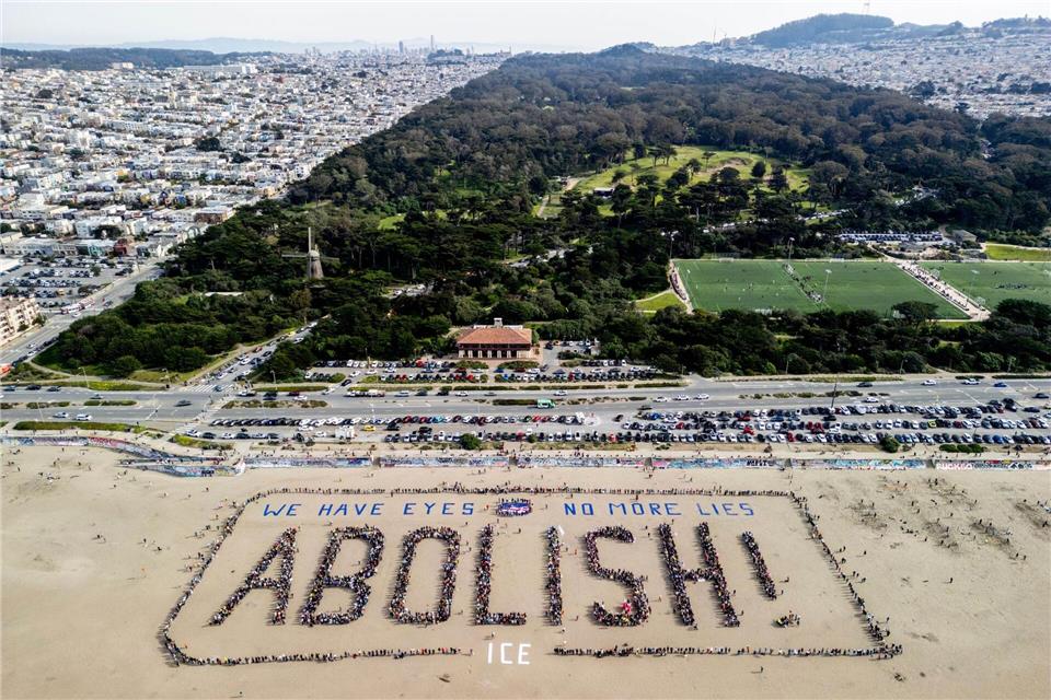 Demonstranten bilden ein menschliches Banner „We have eyes - no more lies - Abolish“ am Ocean Beach in San Francisco während eines Protests gegen die US-Einwanderungsbehörde ICE.Stephen Lam/San Francisco Chronicle via AP/dpa