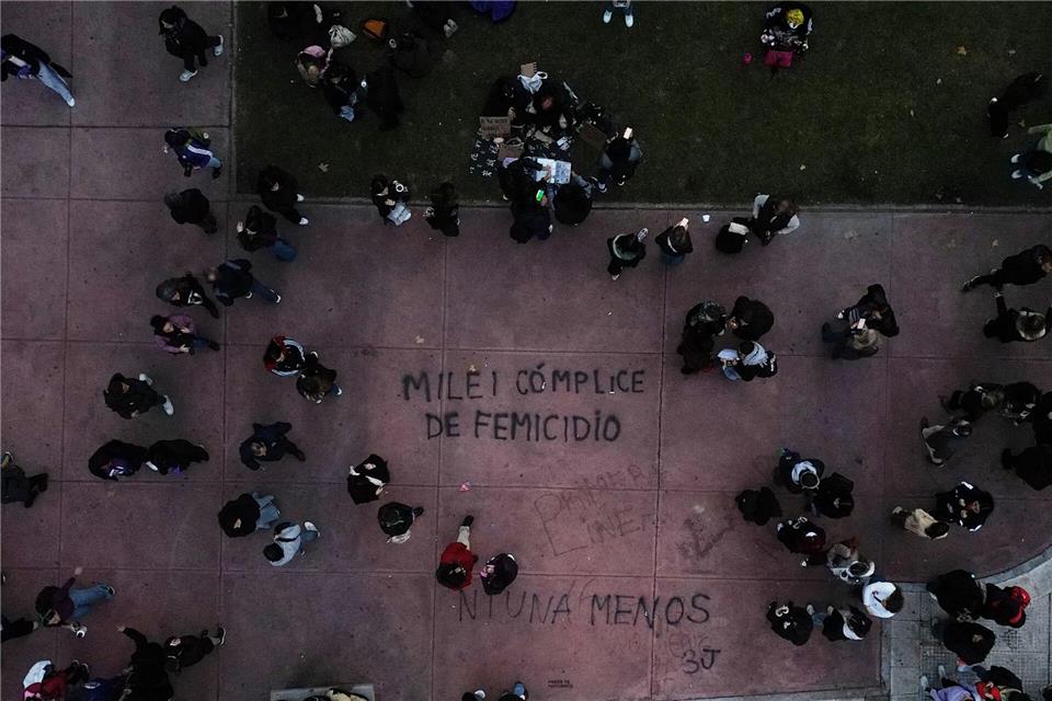 Demonstranten gehen in Buenos Aires in der Nähe eines Schriftzugs „Milei femicide accomplice“ (Milei Frauenmord Mittäter), der sich auf Präsident Javier Milei bezieht, während eines Marsches zum Jahrestag der Frauenbewegung „Ni Una Menos“ (Nicht eine weniger).Natacha Pisarenko/AP/dpa