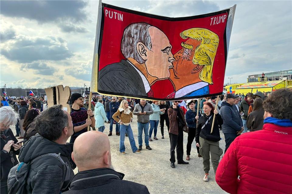 Demonstranten halten bei einer Kundgebung des Bündnisses „Eine Million Augenblicke für Demokratie“ ein Banner, auf dem sich stilisiert US-Präsident Trump und Russlands Präsident Putin küssen.Michael Heitmann/dpa