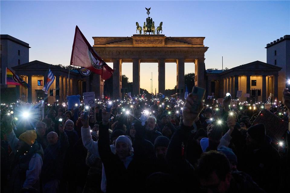 Bilder des Tages Demonstranten halten ihre Handys mit Taschenlampen vor dem Brandenburger Tor in die Luft. Die Demonstration unter dem Motto „Brandmauer hoch! Wir sind das Stadtbild“ bezieht sich auf eine Äußerung von Bundeskanzler Merz im Zusammenhang mit der Migrationspolitik.Annette Riedl/dpa