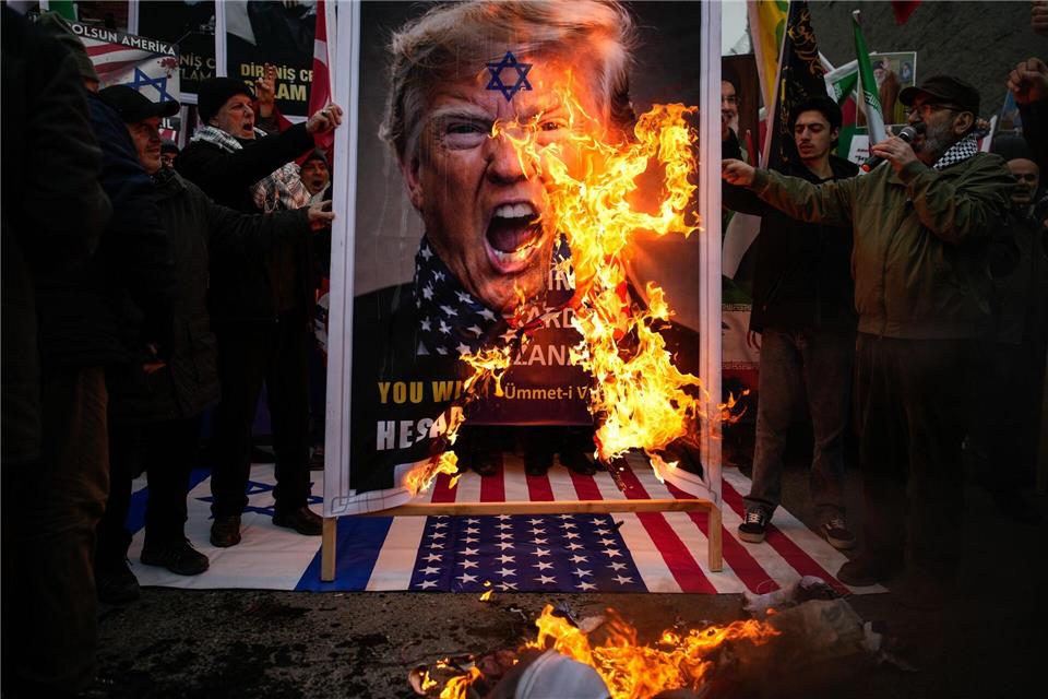 Demonstranten verbrennen ein Poster von US-Präsident Trump während einer Kundgebung gegen die USA und Israel zur Unterstützung der iranischen Regierung vor dem US-Konsulat in Istanbul.Emrah Gurel/AP/dpa