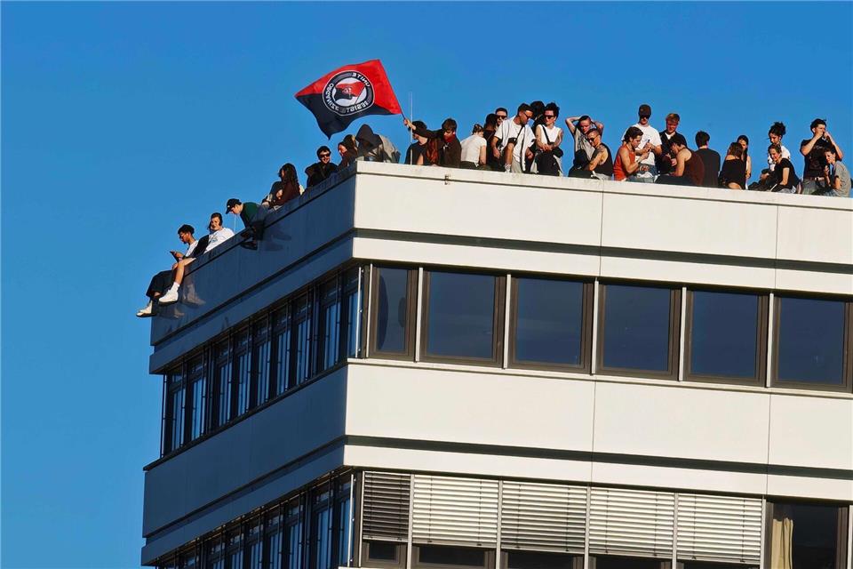 Demonstranten verfolgen ein Konzert vom Dach eines Geschäftshauses.Martin Fischer/dpa-Zentralbild/dpa