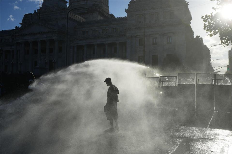 Demonstranten werden in Buenos Aires von einem Wasserwerfer der Polizei besprüht.Rodrigo Abd/AP/dpa