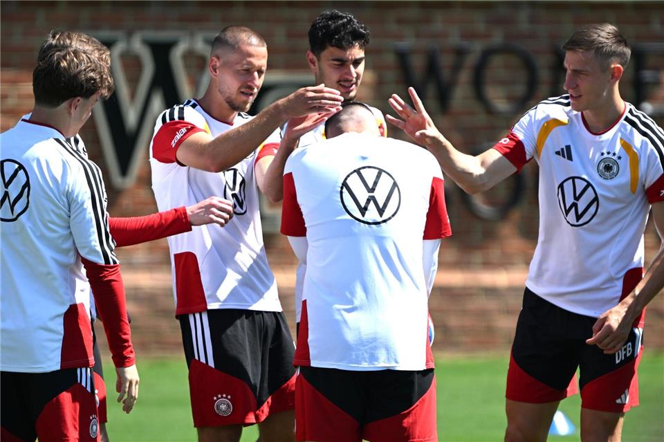 Deniz Undav (M) bekommt beim Kreisspiel von den Kollegen die Ohren geschnippst. Federico Gambarini/dpa