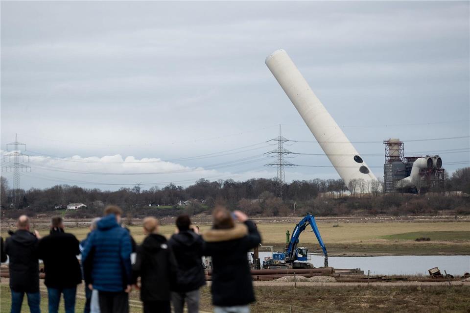 Der 180-Meter-Kamin kippt nach der Sprengung langsam um.Fabian Strauch/dpa