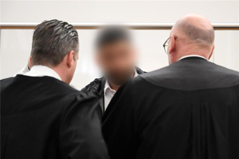 Der Angeklagte (M) spricht im Gerichtssaal mit zwei Strafverteidigern. Zu Prozessbeginn sind weiterhin viele Fragen offen.Shireen Broszies/dpa