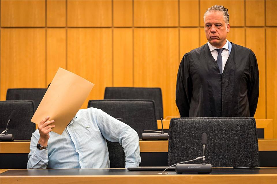 Der Angeklagte hält sich vor Beginn des Prozesses im Saal des Landgerichts einen Umschlag vor das Gesicht. Lars Berg/dpa