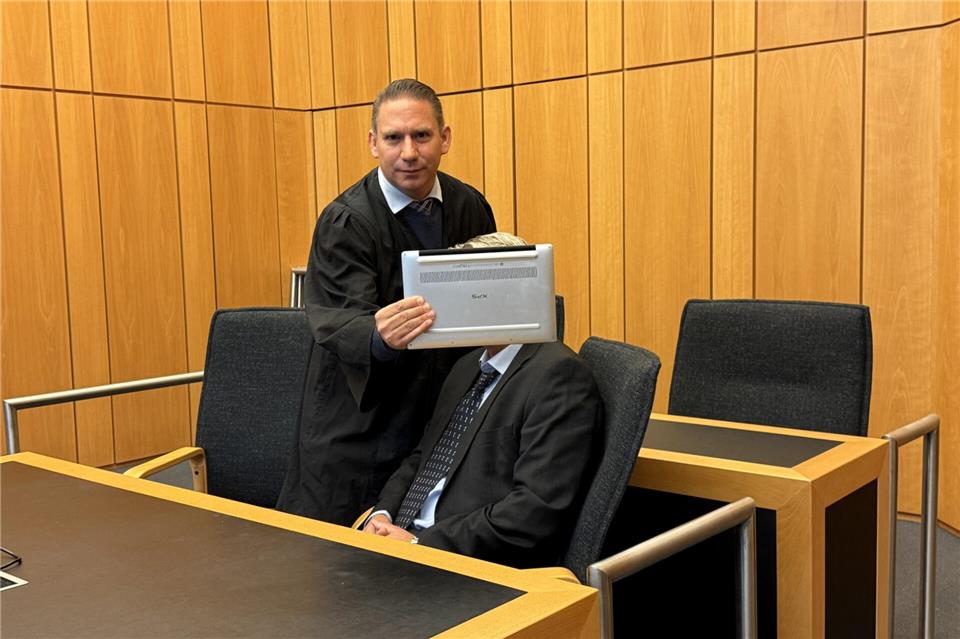 Der Anwalt verdeckt zu Beginn der Verhandlung das Gesicht des Angeklagten.