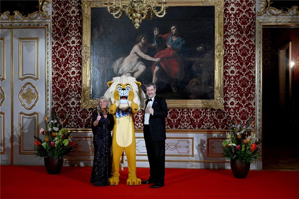 Der Bayerische Ministerpräsident Markus Söder und seine Frau Karin Baumüller-Söder zeigen sich mit einem „Löwen“ beim Neujahrsempfang des Regierungschefs in der Münchner Residenz beim Defilee.Felix Hörhager/dpa