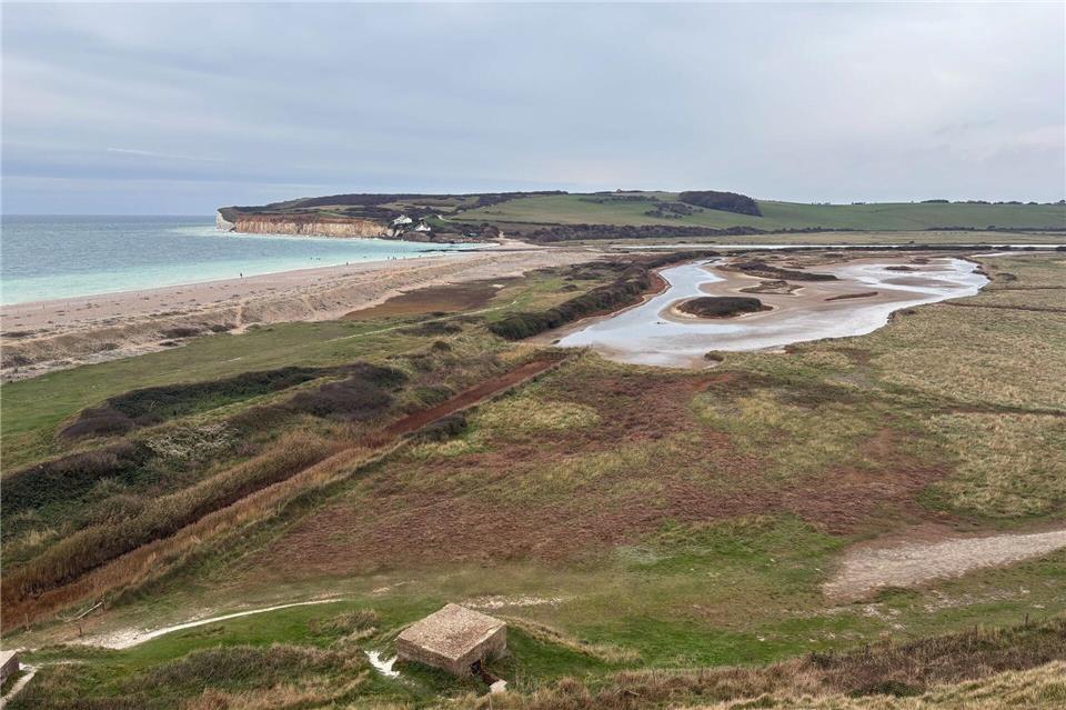 Warum Südengland im Oktober besonders entspannend ist  Der Blick von Haven Brow auf Cuckmere Haven: Bei Ebbe kann man den Strand queren, bei Flut ist das zu gefährlich. Der Umweg zur Brücke landeinwärts lohnt sich aber. Nathalie Helene Rippich/dpa-tmn