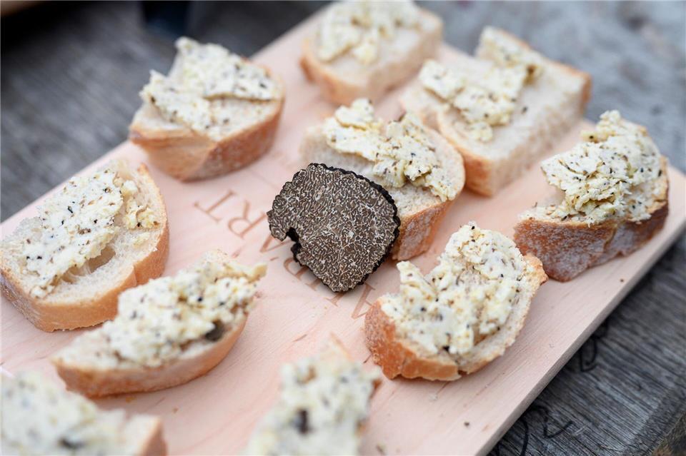 Luxus auf dem Teller: Tipps für den Genuss von Trüffeln Der Burgundertrüffel, (Tuber unicatum) gilt ebenfalls als Delikatesse. Hier liegt ein Stück in der Mitte eines Holzbretts zwischen Appetithäppchen mit Trüffelbutter. picture alliance/dpa