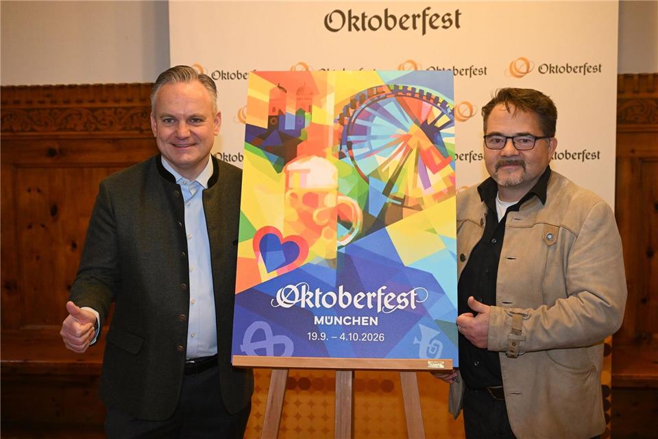 Der Designer Florian Huber zeigt mit Wiesnchef Scharpf sein Wiesn-Motiv. Felix Hörhager/dpa