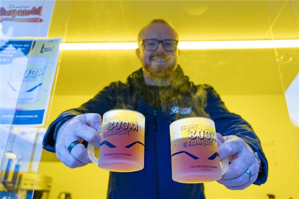 Der Dresdner Unternehmer Benjamin Venter präsentiert in einem Verkaufswagen an der Brühlschen Terrasse zwei der neuen Carolabrücke-Tassen. Jürgen Lösel/dpa