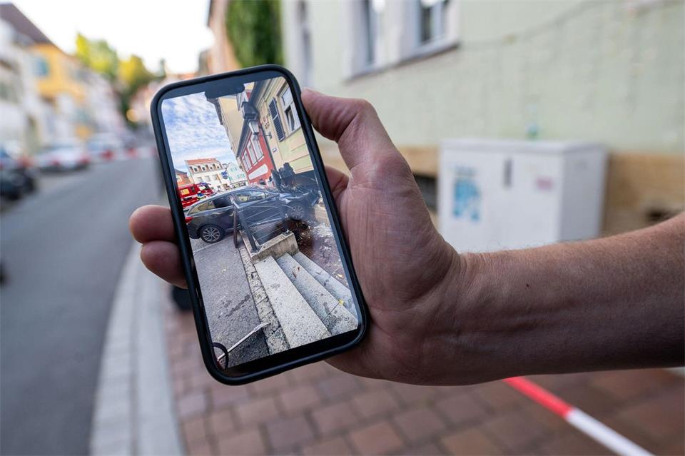 Der Hausbesitzer zeigt auf seinem Handy das Bild von dem Auto, das in der Hauswand steckt.Pia Bayer/dpa